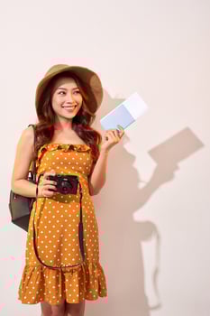 Expressive tourist woman in summer casual clothes, hat holding passport, tickets isolated on beige background. Female traveling abroad to travel weekends getaway. Air flight journey concept photo