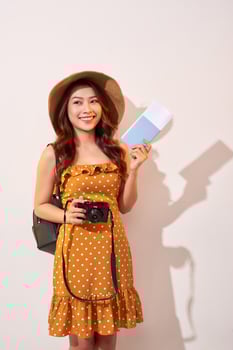Expressive tourist woman in summer casual clothes, hat holding passport, tickets isolated on beige background. Female traveling abroad to travel weekends getaway. Air flight journey concept photo