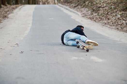 Fail falling from a skateboard. Street style arab man in eyeglasses with longboard longboarding down the road. photo