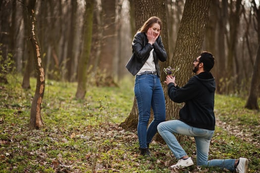 Love story of cool multiracial couple in spring forest. Marriage proposal arab man to european girl. photo