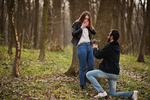 Love story of cool multiracial couple in spring forest. Marriage proposal arab man to european girl. photo