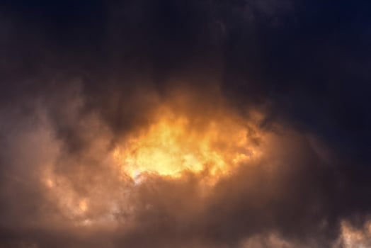 a dark cloud with a bright yellow light coming through photo