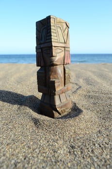 a wooden tiki statue on the beach photo