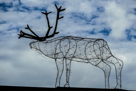 a wire sculpture of a reindeer on top of a roof photo
