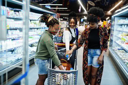 Group of african womans with shopping carts near refrigerator shelf selling dairy products made from milk in the supermarket. photo