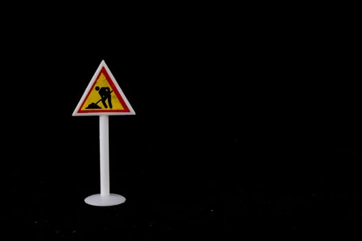 Toy road sign on black background photo