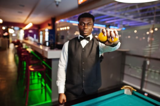 Young handsome african man wearing white shirt, black vest and bow tie play pool billiard. photo