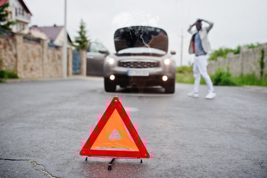 Emergency red warning triangle on the road sign broken suv car of african man. photo