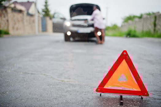 Young sad african woman stand with emergency triangle against car with popped hood. Transportation, vehicles problems and breakdowns concept. photo