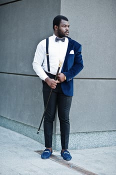 Handsome fashionable african american man in formal wear and bow tie with walking stick. photo