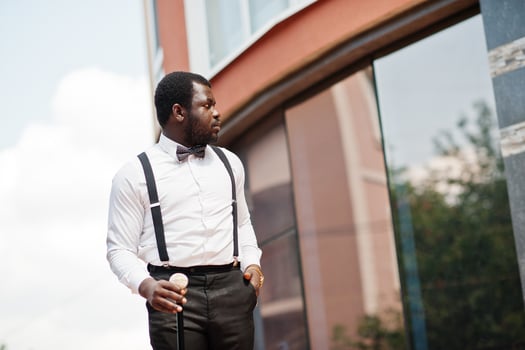 Handsome fashionable african american man in formal wear, bow tie and suspenders, walking stick. photo
