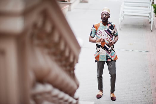 Handsome afro american man wearing traditional clothes, cap and eyeglasses in modern city. photo