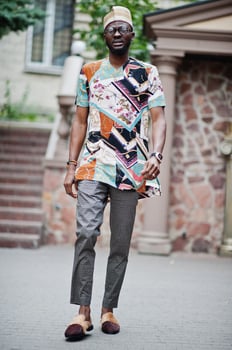 Handsome afro american man wearing traditional clothes, cap and eyeglasses in modern city. photo