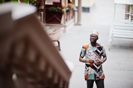 Handsome afro american man wearing traditional clothes, cap and eyeglasses in modern city. photo