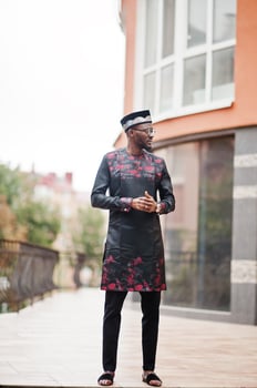 Handsome afro american man wearing traditional clothes, cap and eyeglasses in modern city. photo