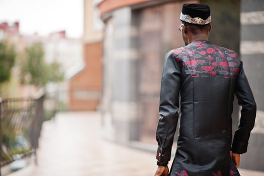 Back of handsome afro american man wearing traditional clothes, cap and eyeglasses in modern city. photo