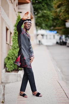 Handsome afro american man wearing traditional clothes, cap and eyeglasses in modern city. photo