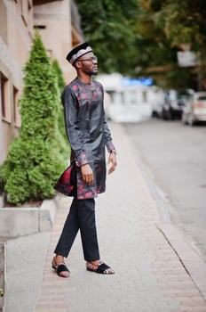 Handsome afro american man wearing traditional clothes, cap and eyeglasses in modern city. photo