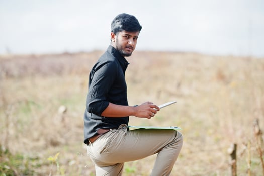 South asian agronomist farmer with clipboard inspecting cut trees in the farm garden. Agriculture production concept. photo