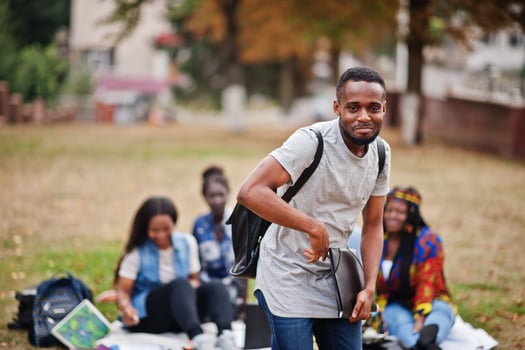 Group of five african college students spending time together on campus at university yard. Black afro friends studying. Education theme. photo