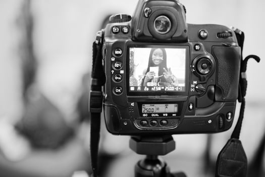 Cute african american woman making a video for her blog using a tripod mounted digital camera. Young female blogger or vlogger on camera. photo