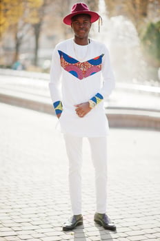 Stylish trendy afro france man in red hat and white outfit posed at autumn day. Black african model guy against fountain. photo
