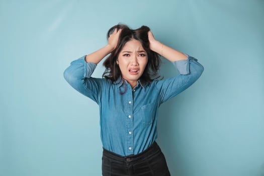 Portrait of young Asian woman isolated by blue background feeling frustrated with helpless face expression. photo