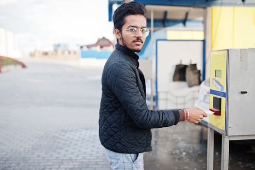 South asian man or indian male washing his white transportation on car wash. His putting money into the atm machine. photo