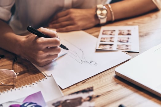 Best designs. Close up top view of young woman working on sketches while sitting in her workshop photo