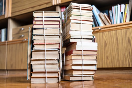 two stacks of old books tied with twine on floor photo