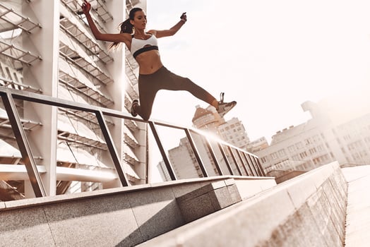 Towards a healthier lifestyle. Full length of modern young woman in sports clothing jumping while exercising outdoors photo