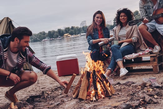 Carefree time with friends. Group of young people in casual wear smiling while enjoying beach party near the campfire photo