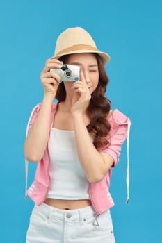 Smiling woman with travel case holding photo camera. Traveler girl isolated portrait.