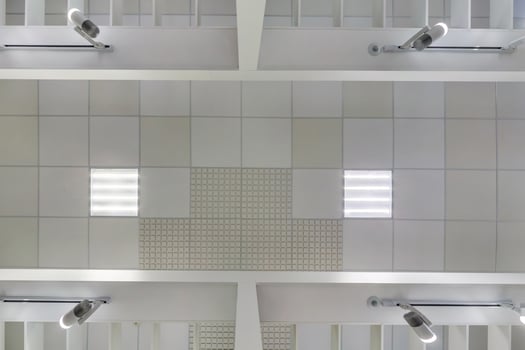 cassette suspended ceiling with square halogen spots lamps and drywall construction in empty room in apartment or house. Stretch ceiling white and complex shape. Looking up view photo