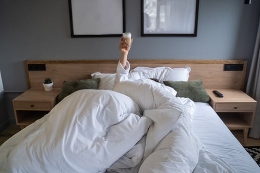 Hand holding a cup of coffee at home in bed photo