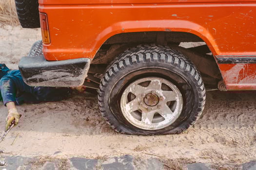 man lies under a 4x4 car on a dirt road photo
