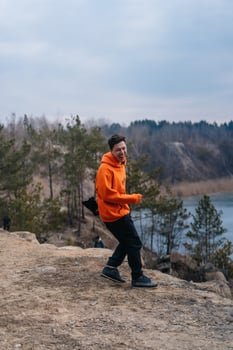 A young man standing on the edge of a cliff poses for the camera photo