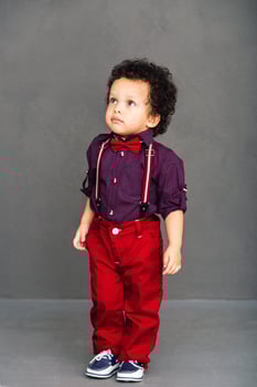 I am ready for a date Little African baby boy looking away while standing against grey background photo