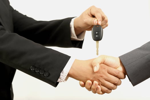 Salesman is carrying the car keys delivered to the customer at the showroom with a low interest offer. Special promotion photo