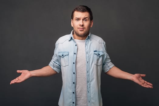 What else can I do Young man keeping arms outstretched and looking at camera while standing against grey background photo