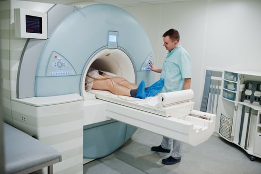 Male doctor turns on magnetic resonance imaging machine with patient inside. photo
