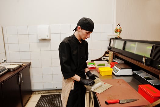 Professional chef wear in black making sushi and rolls in a restaurant kitchen of japanese traditional food. photo