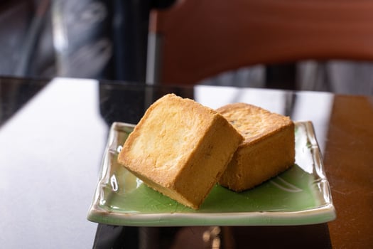 Delicious pineapple pastry in a plate for afternoon tea on wooden railing of a teahouse in Taiwan with beautiful landscape in background, close up. photo
