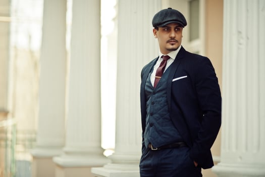 Portrait of retro 1920s english arabian business man wearing dark suit, tie and flat cap. photo