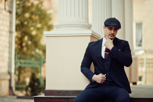Portrait of retro 1920s english arabian business man wearing dark suit, tie and flat cap. photo