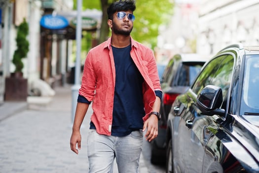Portrait of young stylish indian man model pose in street in sunglasses against car. photo