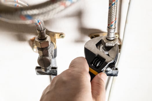 plumber hand fixes connection of tap by wrench photo
