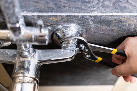 plumber unscrews nut of shower faucet close up photo