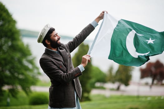 Beard pakistani man wear pakol hat and jacket hold Pakistan flag. photo