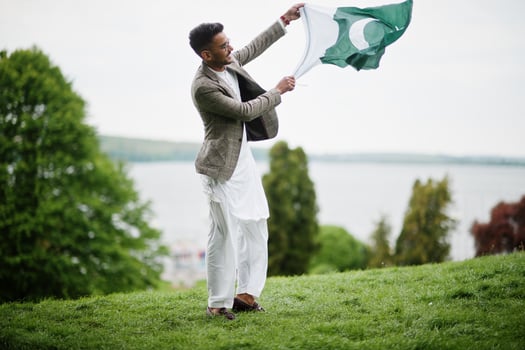 Stylish pakistani man wear in eyeglasses and jacket hold Pakistan flag. photo